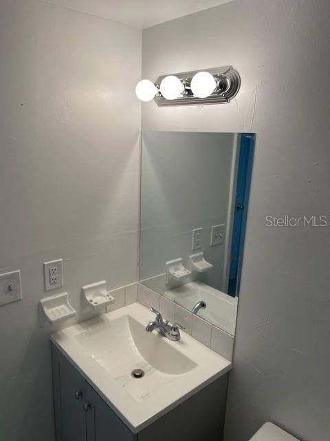 half bath featuring backsplash and vanity