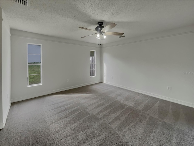 empty room with ceiling fan, plenty of natural light, carpet flooring, and visible vents