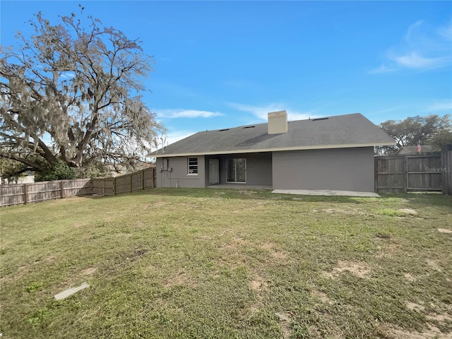 back of property featuring a fenced backyard, a lawn, and a chimney