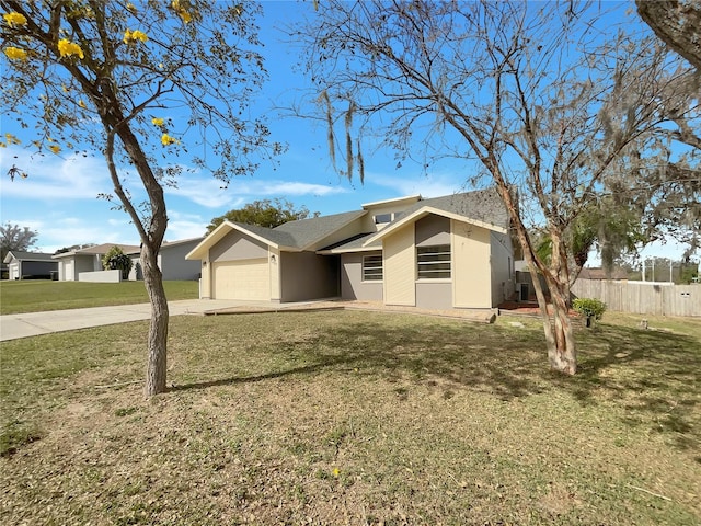 view of front of property featuring an attached garage, fence, concrete driveway, stucco siding, and a front lawn