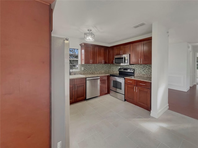 kitchen featuring visible vents, appliances with stainless steel finishes, decorative backsplash, and light stone counters