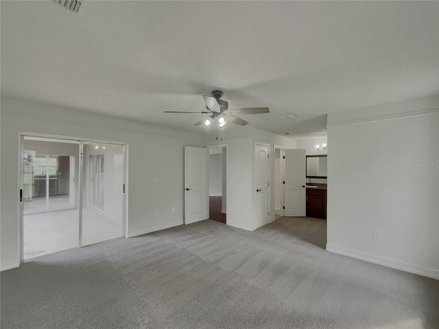 unfurnished bedroom featuring baseboards, ensuite bath, visible vents, and light colored carpet