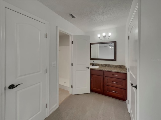 full bath featuring visible vents, walk in shower, a textured ceiling, and vanity