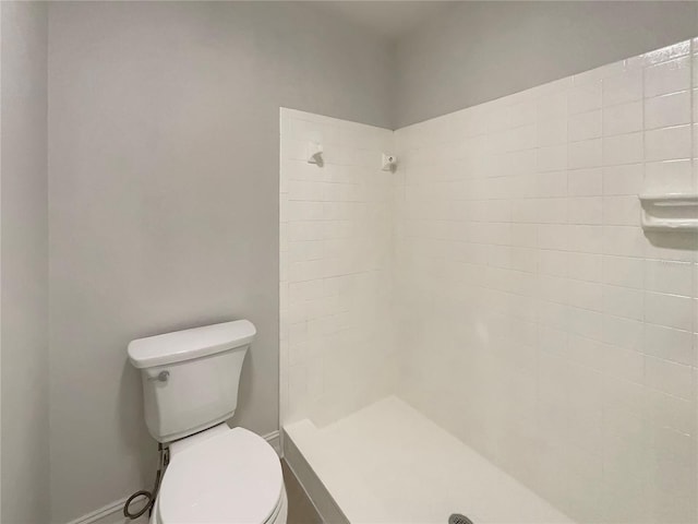 bathroom featuring tiled shower and toilet