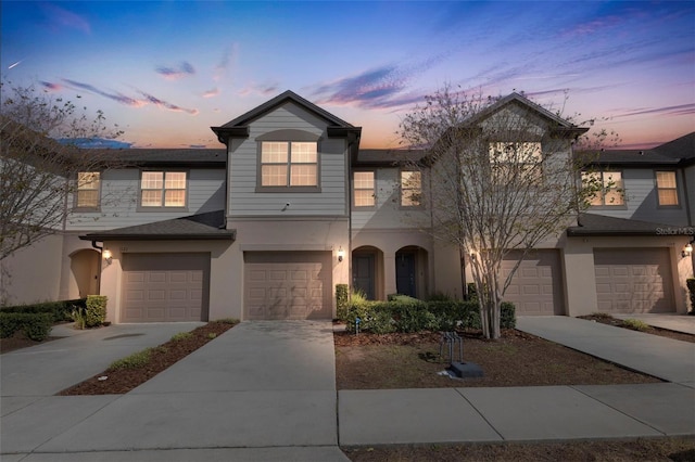 view of property featuring a garage, driveway, and stucco siding