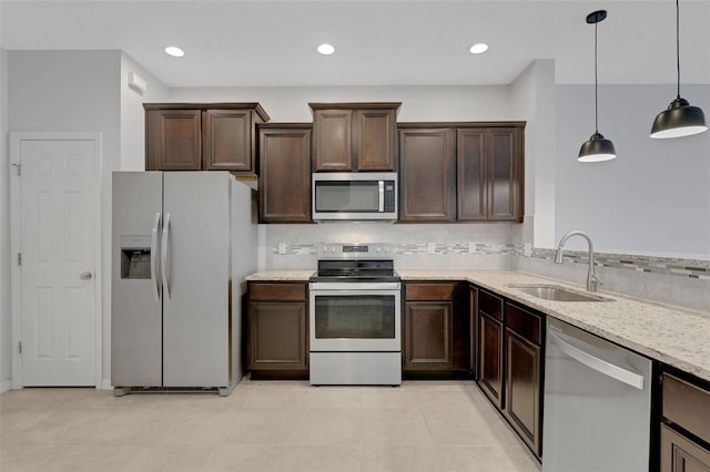 kitchen featuring stainless steel appliances, a sink, light stone counters, and dark brown cabinets