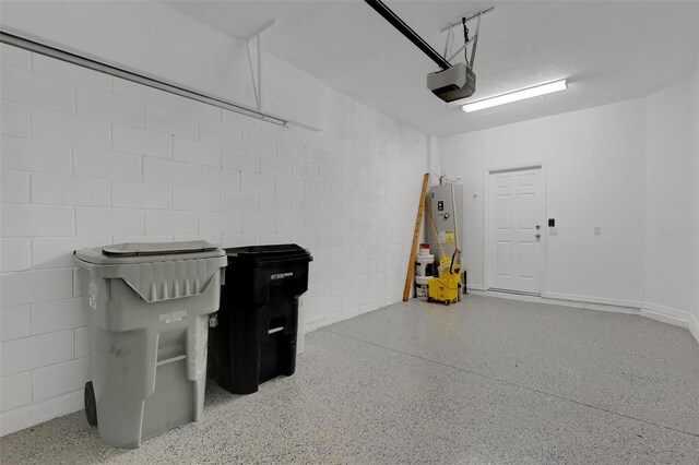 garage featuring gas water heater, concrete block wall, and a garage door opener