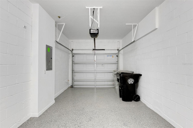 garage with concrete block wall, electric panel, and a garage door opener