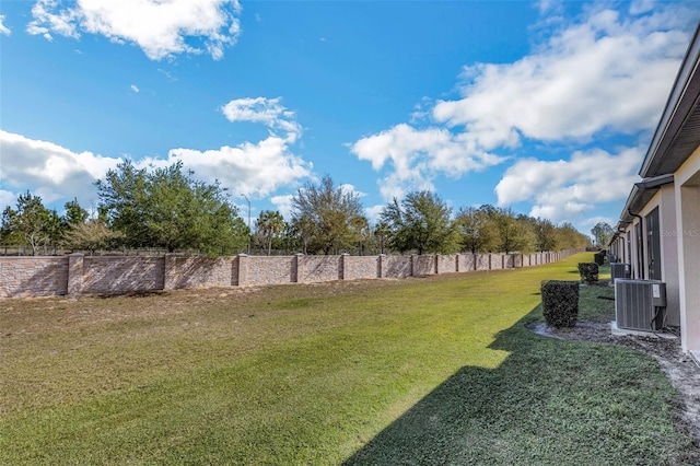 view of yard with central AC and fence