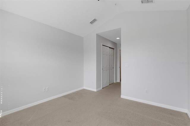 unfurnished room featuring light carpet, lofted ceiling, visible vents, and baseboards