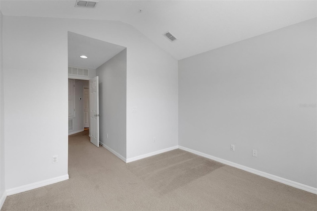 spare room with lofted ceiling, visible vents, and carpet flooring