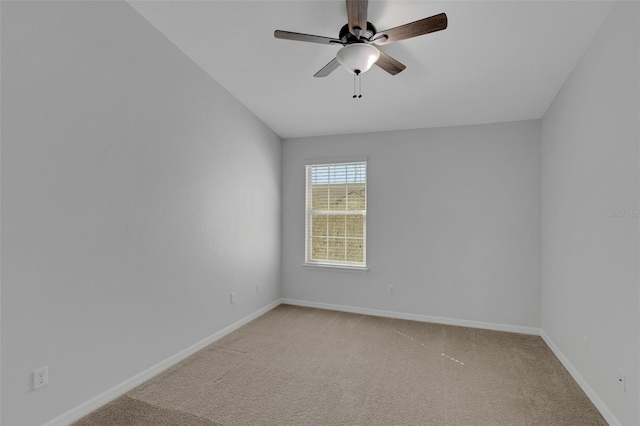 spare room with baseboards, a ceiling fan, and light colored carpet