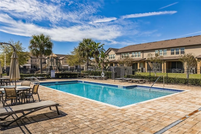 pool with a residential view, fence, and a patio