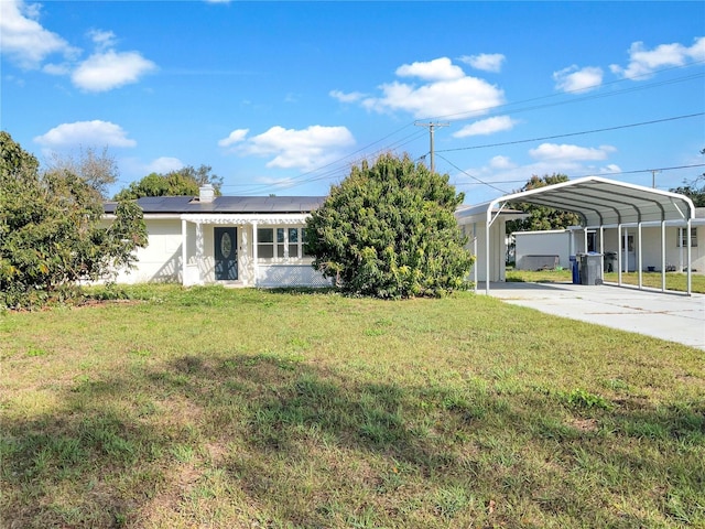 view of front facade with solar panels, a front lawn, concrete driveway, and a detached carport