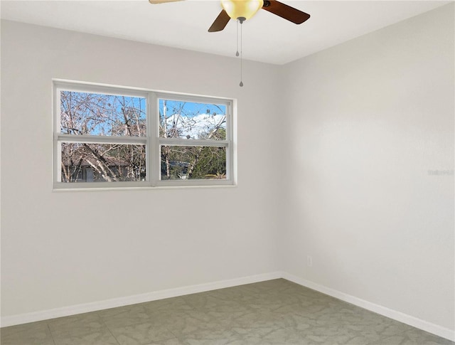 spare room featuring a ceiling fan and baseboards