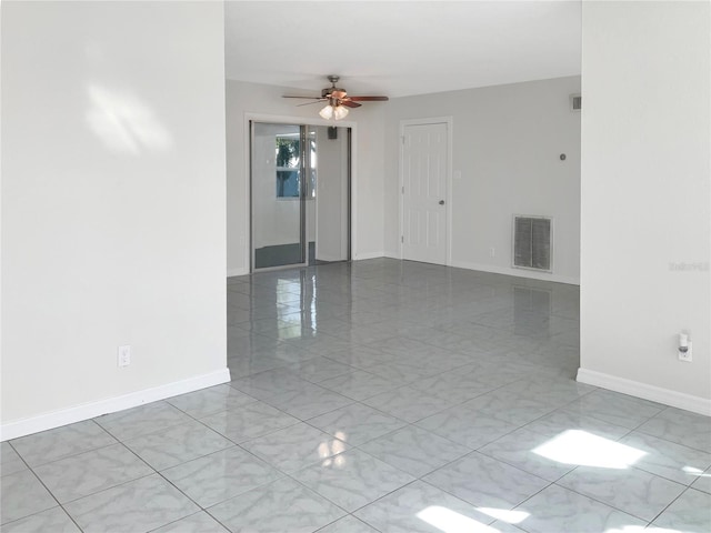 unfurnished room with baseboards, visible vents, and ceiling fan