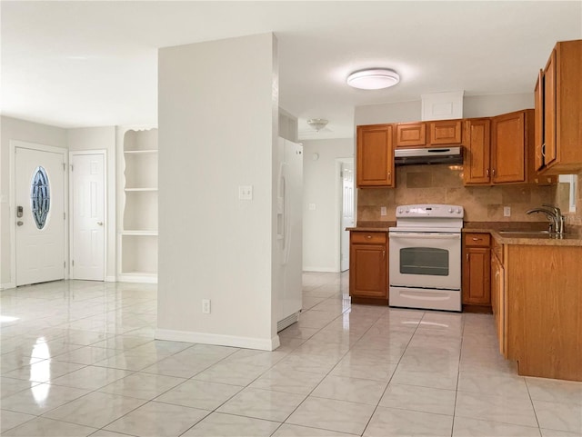 kitchen with under cabinet range hood, white appliances, a sink, backsplash, and brown cabinets