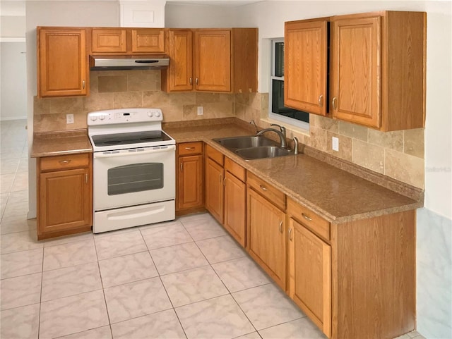 kitchen featuring under cabinet range hood, electric range, a sink, backsplash, and brown cabinetry