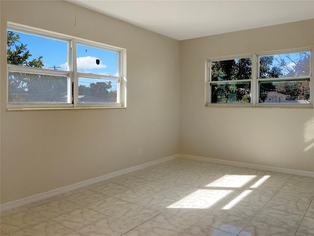 spare room featuring marble finish floor and baseboards