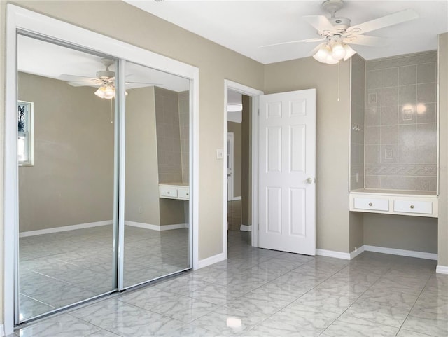 unfurnished bedroom with marble finish floor, baseboards, a closet, and built in study area