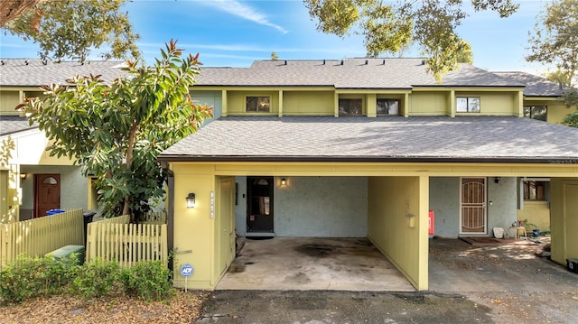 view of front of home featuring roof with shingles, fence, and stucco siding