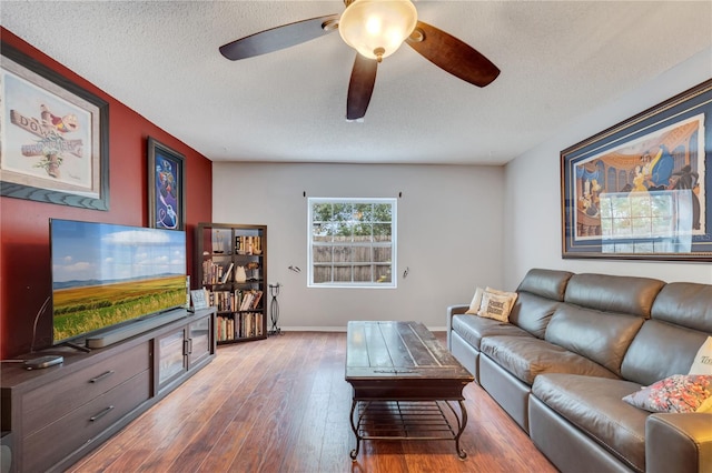 living room featuring hardwood / wood-style flooring, a ceiling fan, baseboards, and a textured ceiling