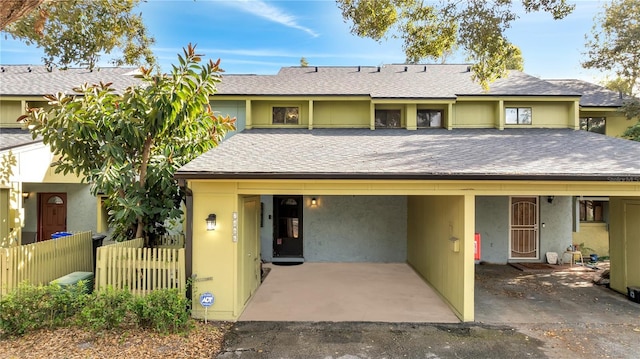 view of front of home with stucco siding, roof with shingles, and fence