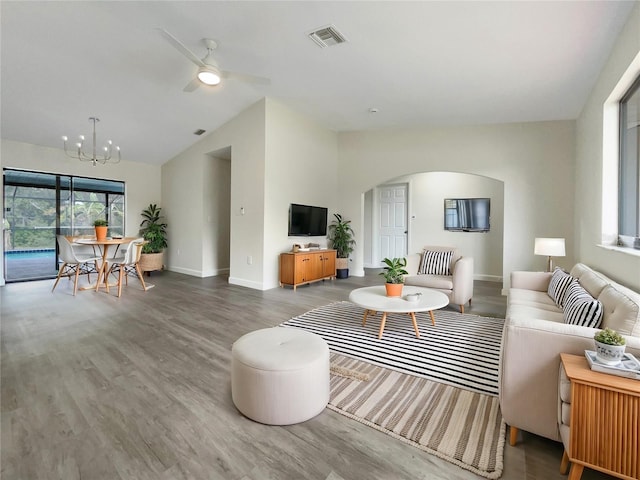 living area with baseboards, visible vents, arched walkways, lofted ceiling, and wood finished floors