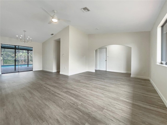 empty room with arched walkways, lofted ceiling, visible vents, wood finished floors, and ceiling fan with notable chandelier