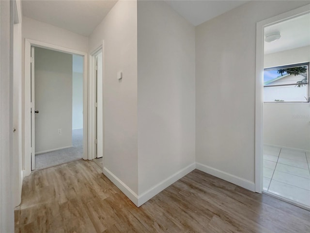 hall with light wood-type flooring and baseboards