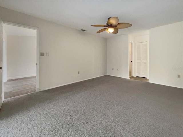 unfurnished room with carpet floors, visible vents, baseboards, and a ceiling fan