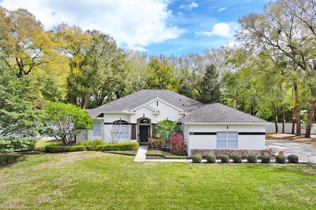 ranch-style home with an attached garage, a shingled roof, driveway, stucco siding, and a front lawn