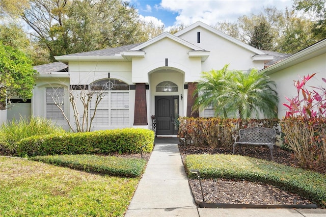 view of front of home with a shingled roof and stucco siding