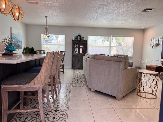 living room with a healthy amount of sunlight, visible vents, a textured ceiling, and light tile patterned floors