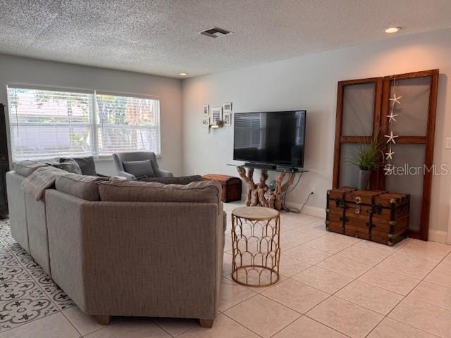 living area featuring visible vents, a textured ceiling, baseboards, and light tile patterned floors