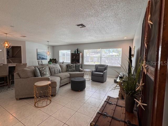 living room with visible vents, a textured ceiling, and light tile patterned flooring