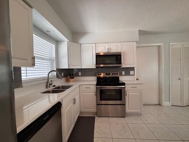 kitchen featuring light countertops, appliances with stainless steel finishes, a sink, and white cabinets