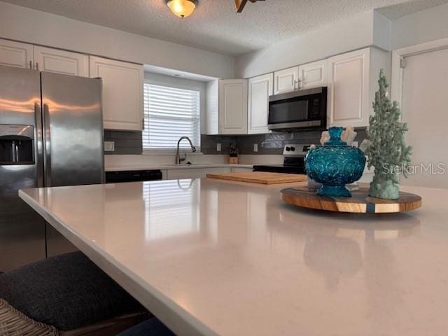 kitchen featuring appliances with stainless steel finishes, light countertops, white cabinetry, and decorative backsplash