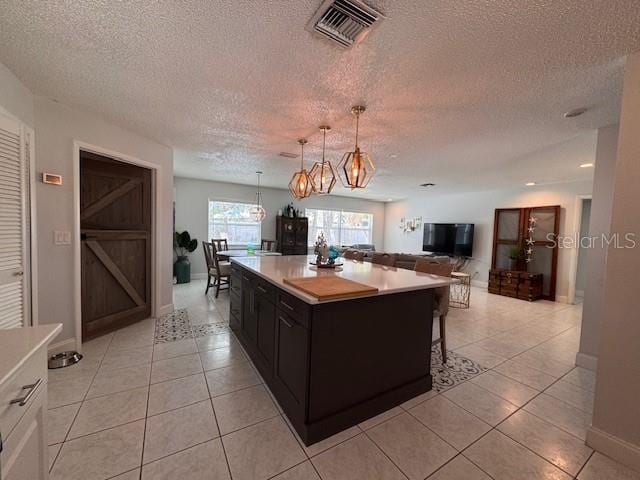 kitchen with light countertops, visible vents, open floor plan, light tile patterned flooring, and a kitchen breakfast bar