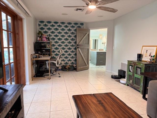 office space with visible vents, a barn door, an accent wall, light tile patterned flooring, and wallpapered walls