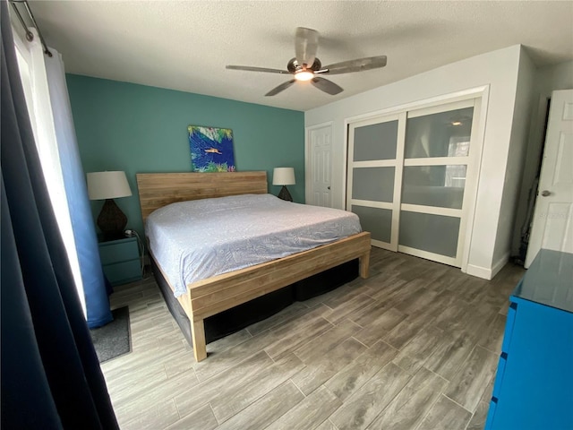 bedroom featuring a textured ceiling, a closet, wood finished floors, and a ceiling fan