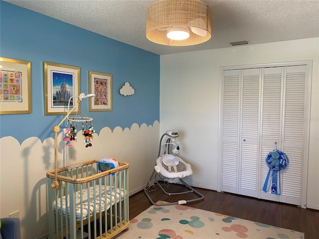 bedroom featuring a closet, visible vents, a textured ceiling, and wood finished floors