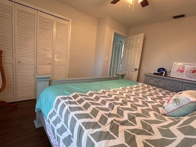 bedroom featuring dark wood-style floors, ceiling fan, a closet, and visible vents