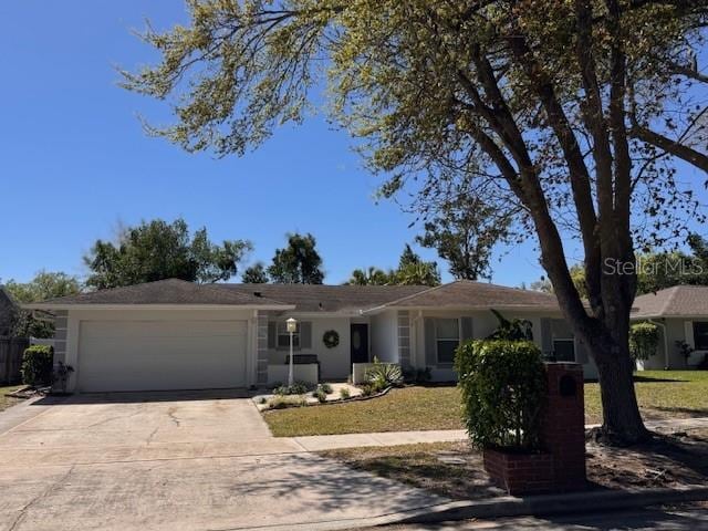 ranch-style house featuring concrete driveway, a front yard, an attached garage, and stucco siding