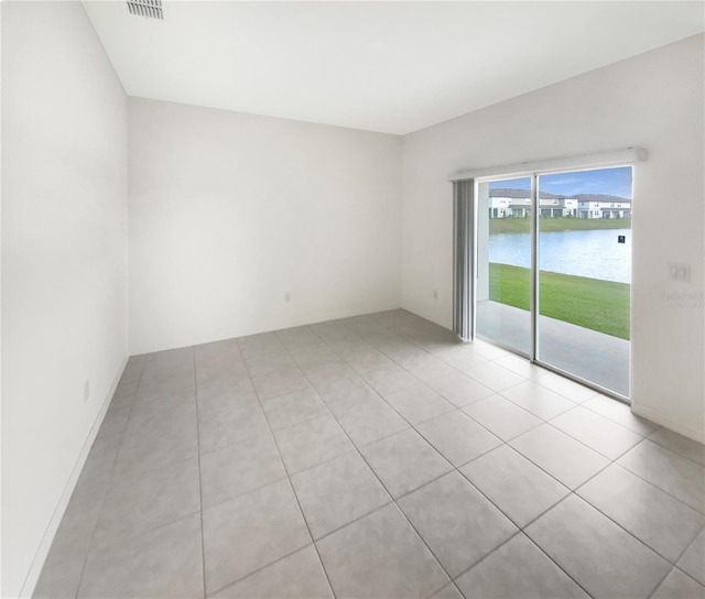 empty room featuring a water view and light tile patterned floors