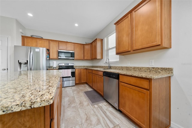 kitchen with light stone counters, brown cabinets, stainless steel appliances, recessed lighting, and a sink