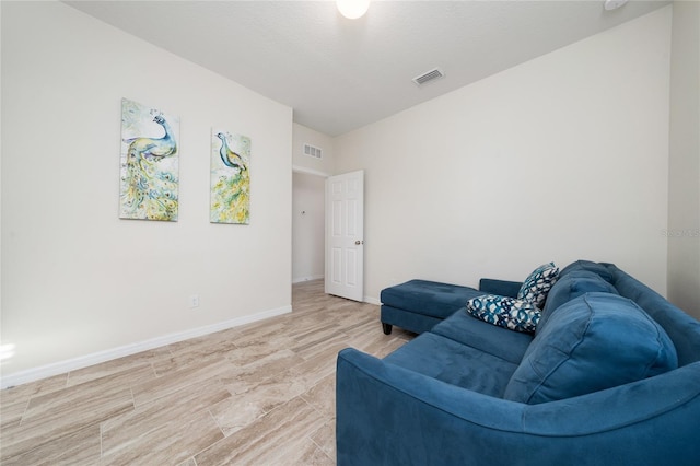 living area featuring light wood-style floors, baseboards, visible vents, and a textured ceiling