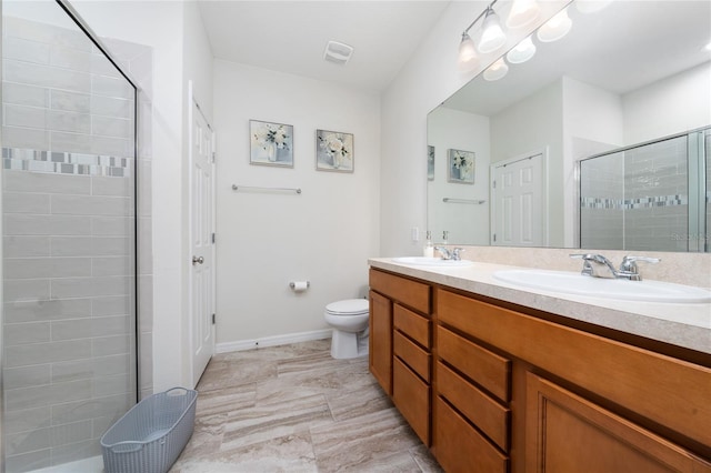 bathroom featuring toilet, a stall shower, double vanity, and a sink