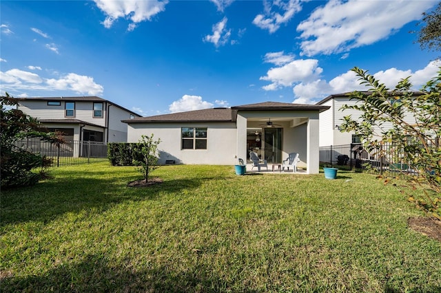 rear view of property featuring a yard, a fenced backyard, a ceiling fan, and stucco siding