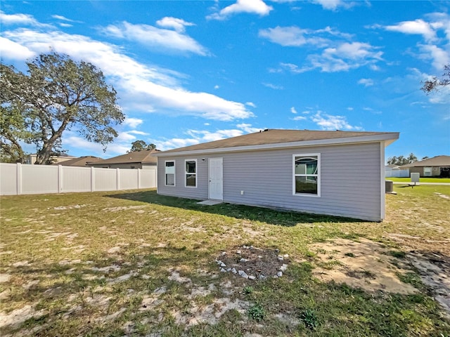 rear view of property with a yard and fence